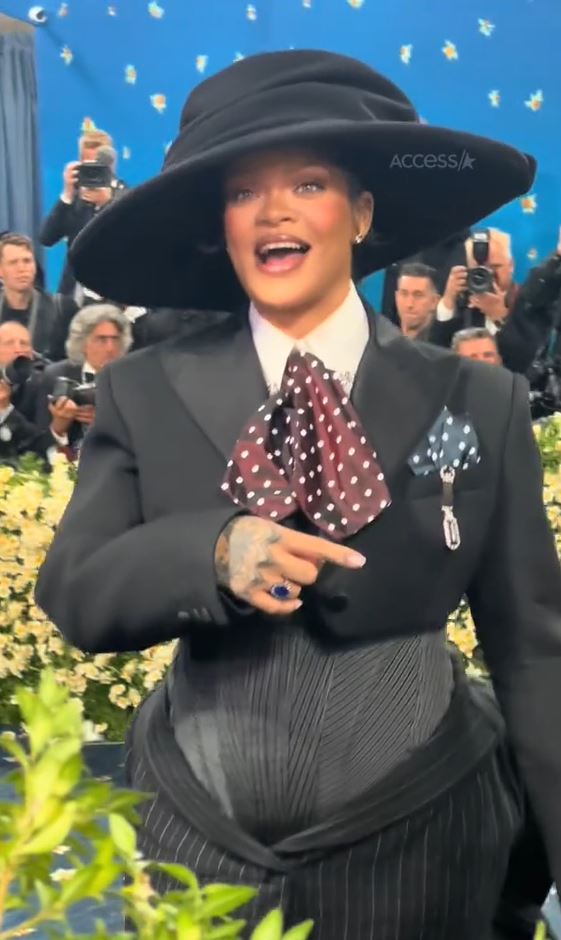 Rihanna at the Met Gala in a black suit and large hat.