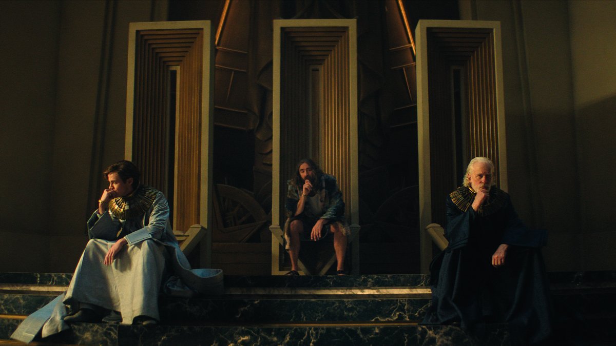 Three people seated near a throne on Foundation