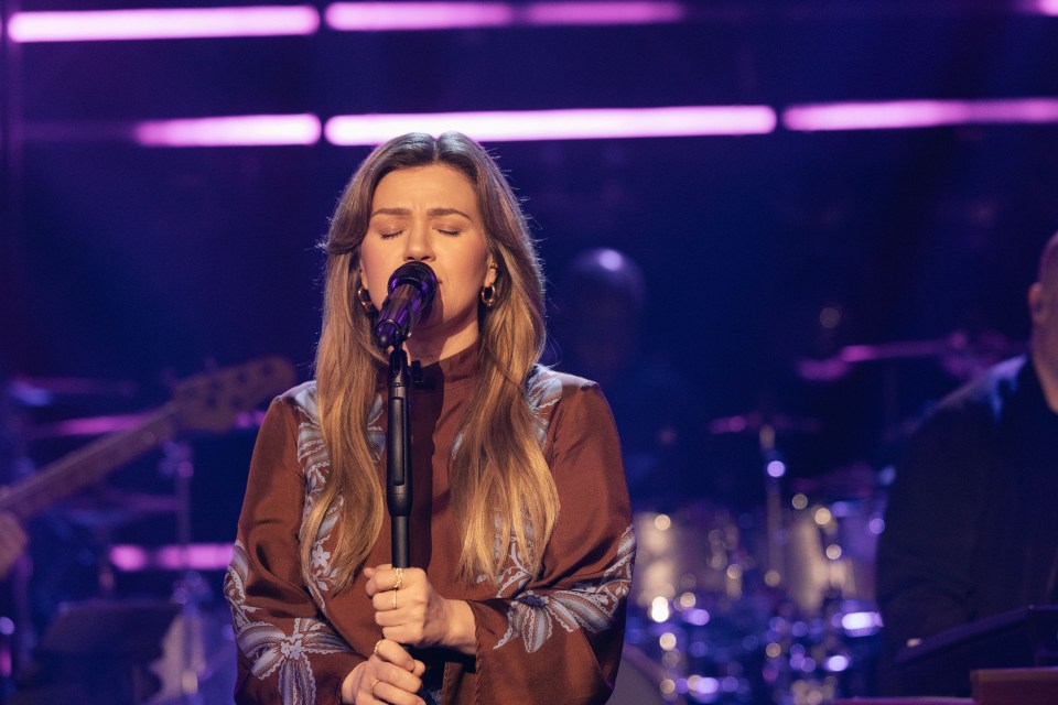 Kelly Clarkson singing into a microphone on stage.