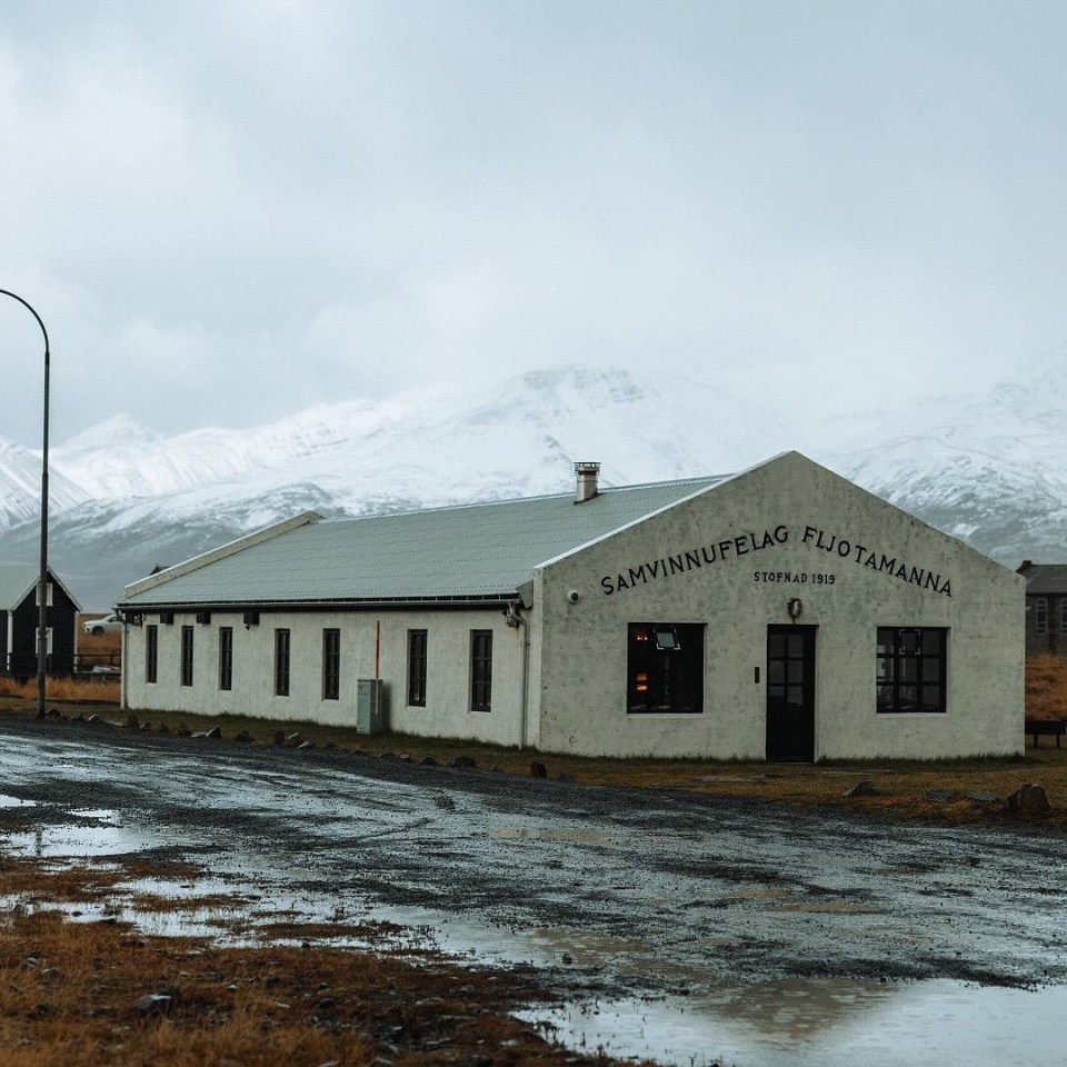 Long, low building with snow-capped mountains in the background.