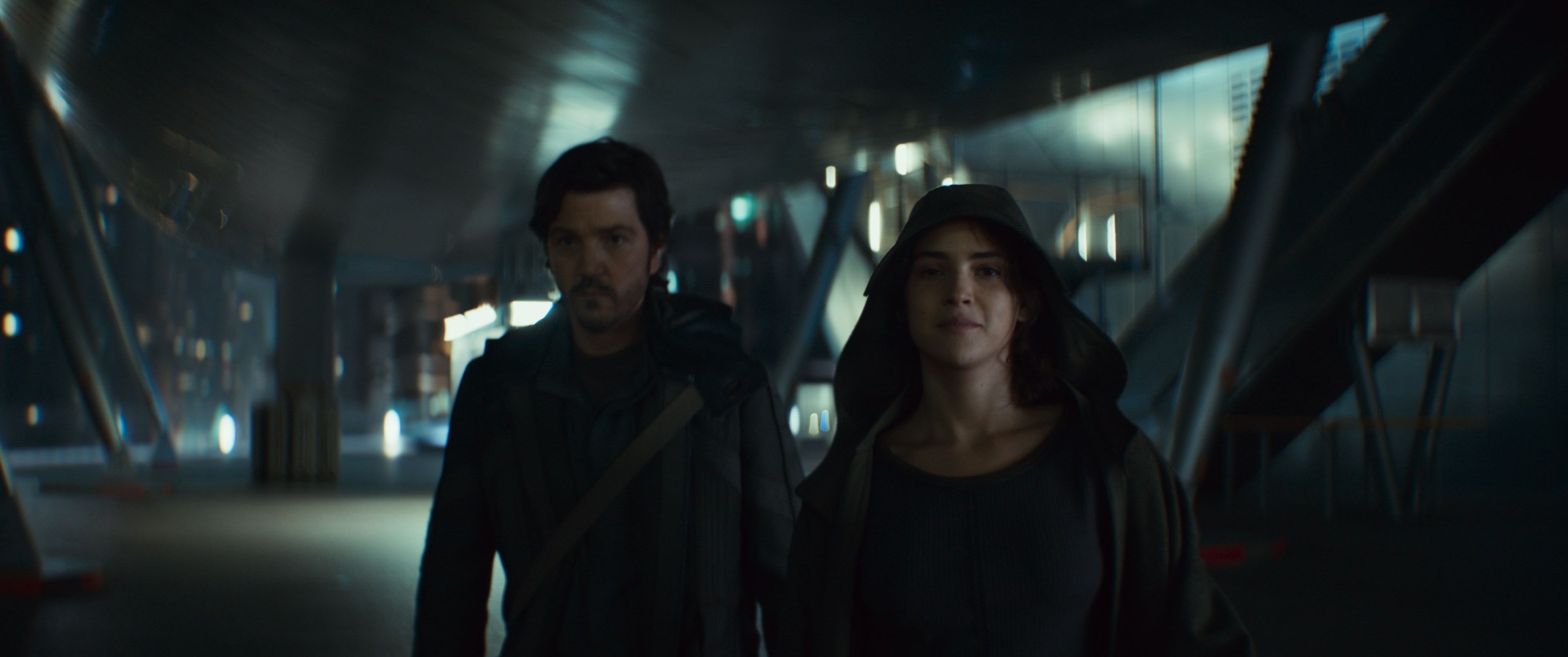 Cassian Andor (Diego Luna) and Bix Caleen (Adria Arjona), looking grimly determined, walk toward the camera in Andor season 2