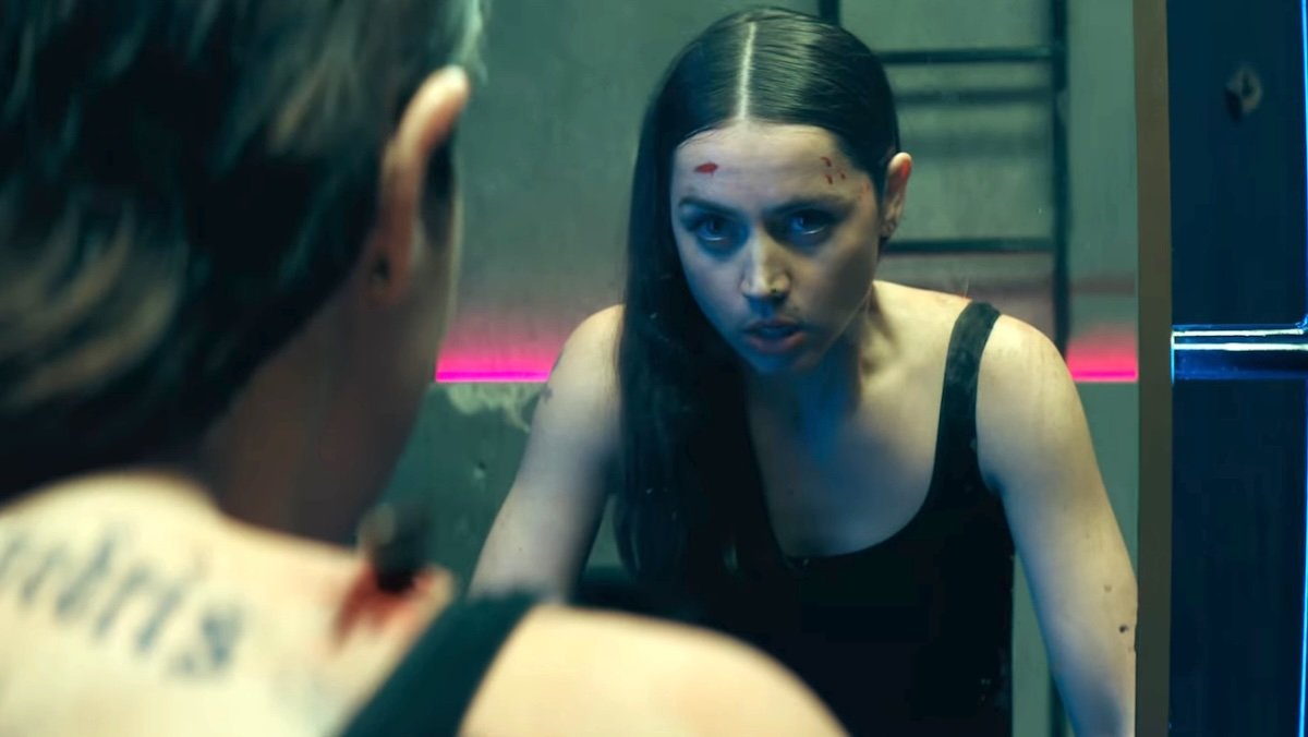 A blooded Ana de Armas looks at herself in the mirror in Ballerina