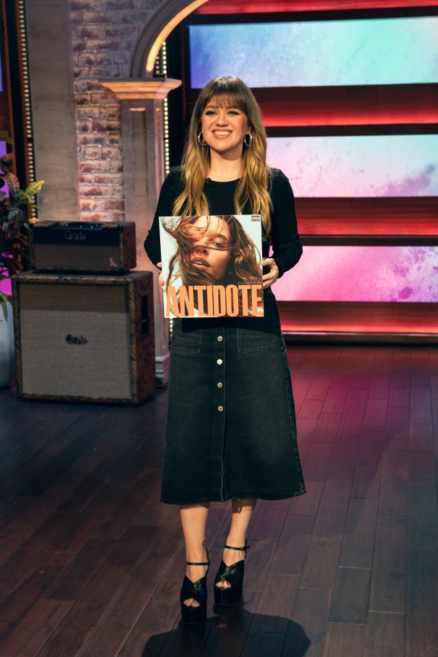 Kelly Clarkson holding the album "In Search of the Antidote."