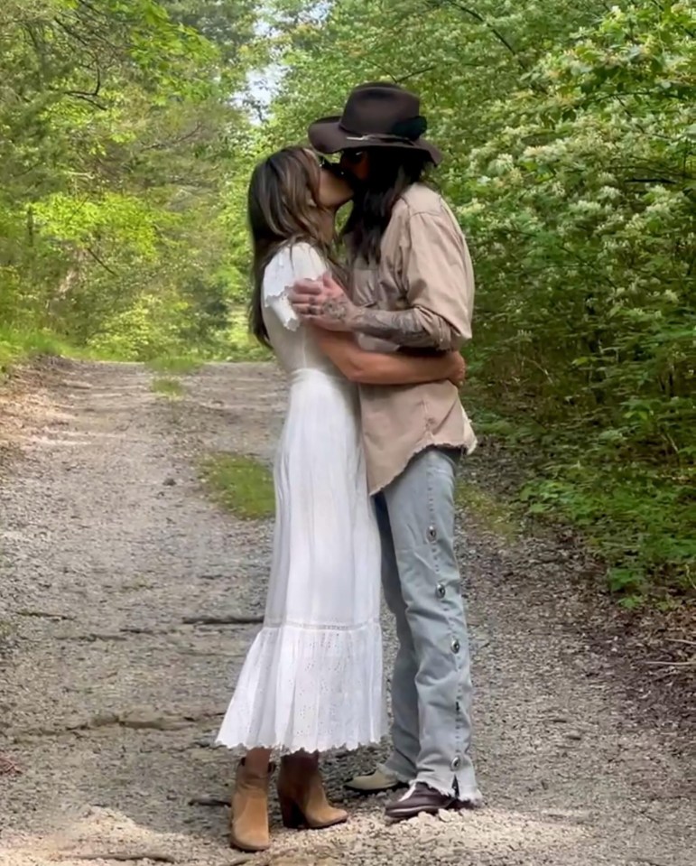 A couple kissing on a dirt path.