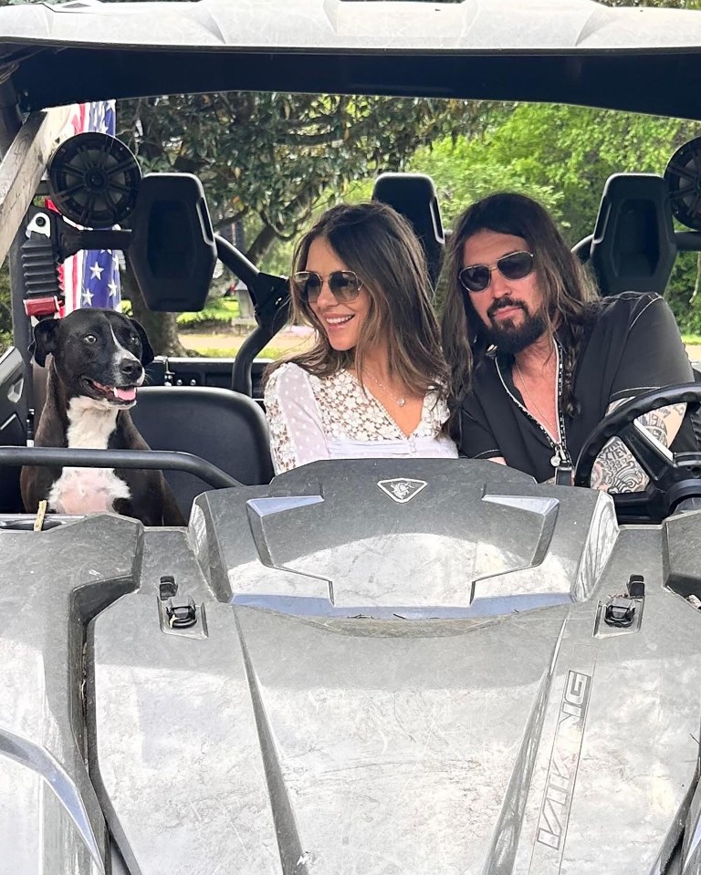 Liz Hurley, Billy Ray Cyrus, and their dog in a side-by-side.