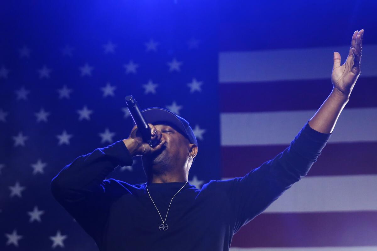 Man standing in front of an American flag w/ a microphone