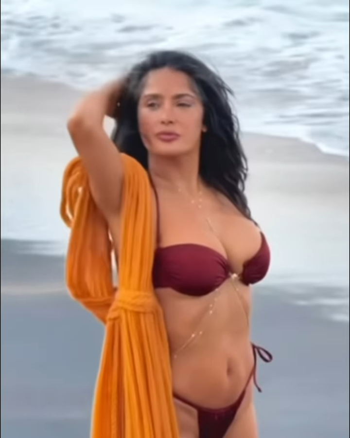 Salma Hayek in a maroon bikini on a beach.