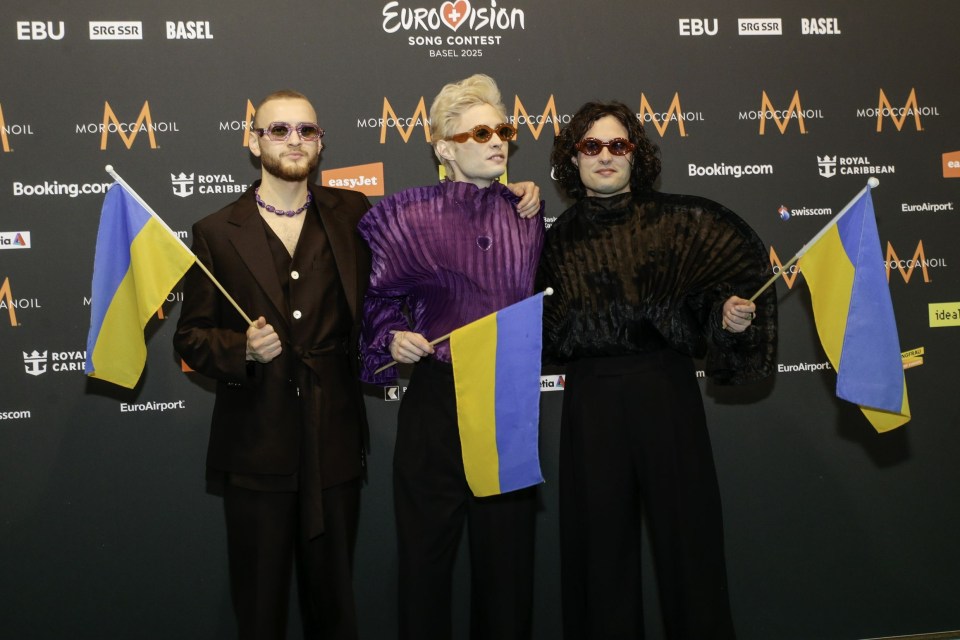 Three members of the Ukrainian Eurovision Song Contest entry posing with Ukrainian flags.
