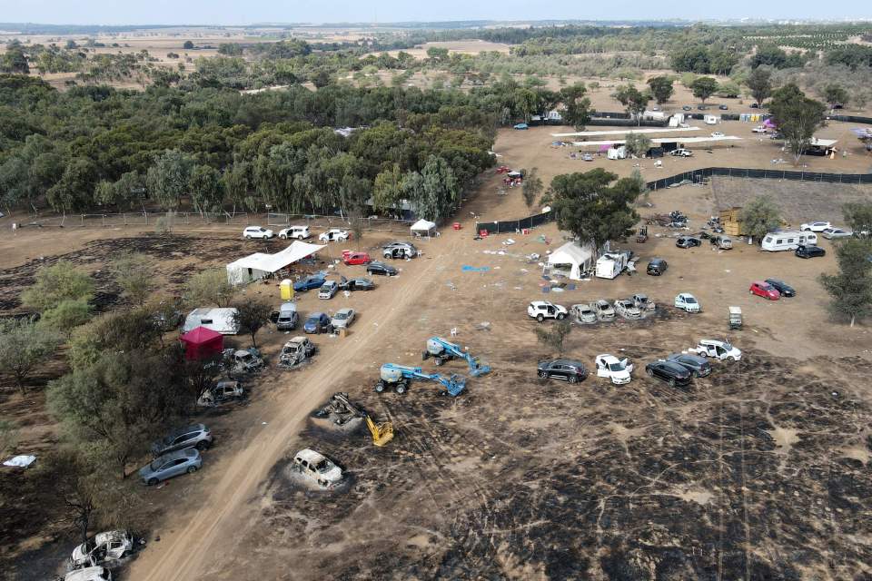 Aerial view of the aftermath of an attack at a music festival, showing burned cars and damaged structures.