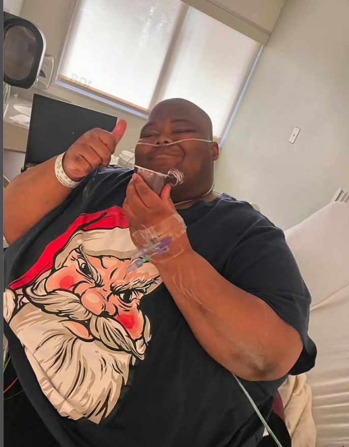 Rapper Dave Blunts giving a thumbs-up while in a hospital bed.