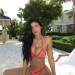Kylie Jenner in a red jeweled bikini by the pool.