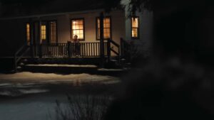 Joel from a distance seen sitting on his porch at night holding a guitar on The Last of Us