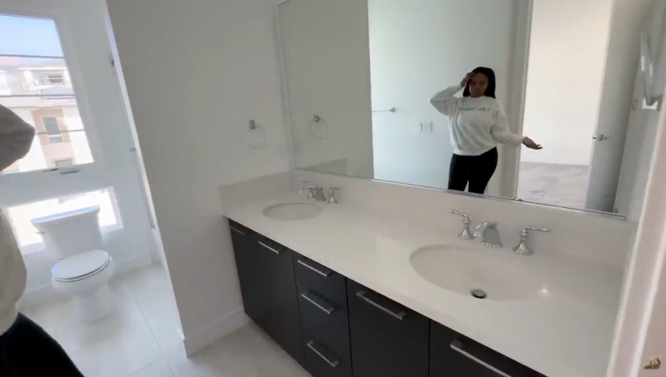 Woman standing in a modern bathroom with double sinks.