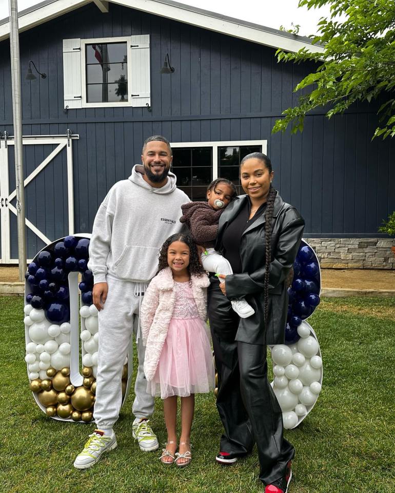 Family photo in front of a dark-blue building with balloon numbers.