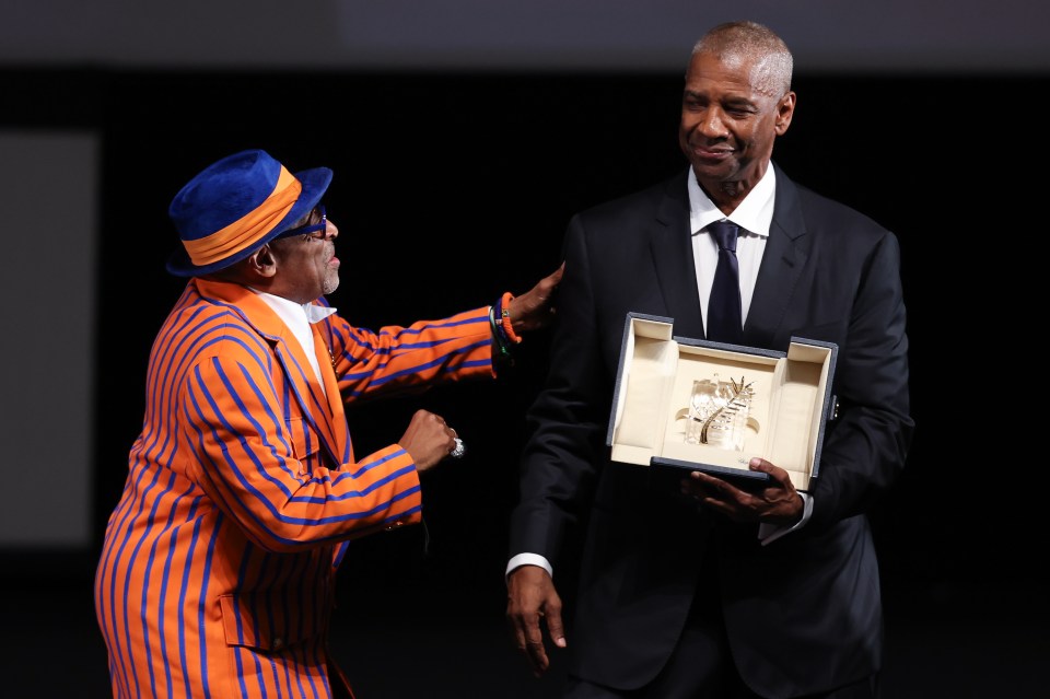 Denzel Washington receives the Honorary Palme d'Or from Spike Lee at the Cannes Film Festival.