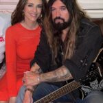Liz Hurley and Billy Ray Cyrus sitting together.