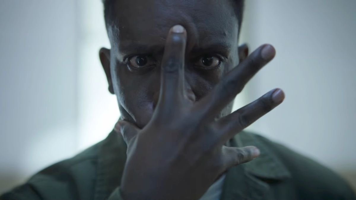 imagine of a man holding his hand over his face with a sinister look in his eyes in welcome to derry trailer