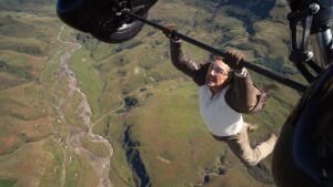 Tom Cruise hanging from a flying biplane high above the ground in Mission: Impossible - The Final Reckoning