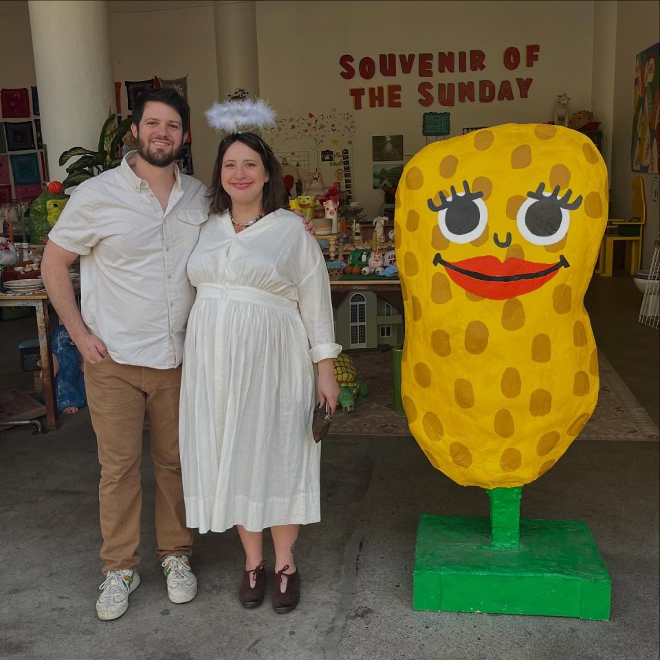 Pregnant woman and man posing in front of a large corn sculpture.