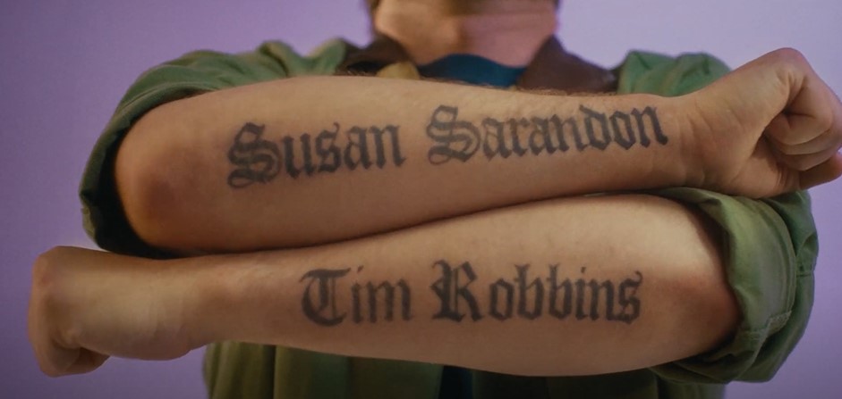 Person's arms with "Susan Sarandon" and "Tim Robbins" tattooed in old English font.