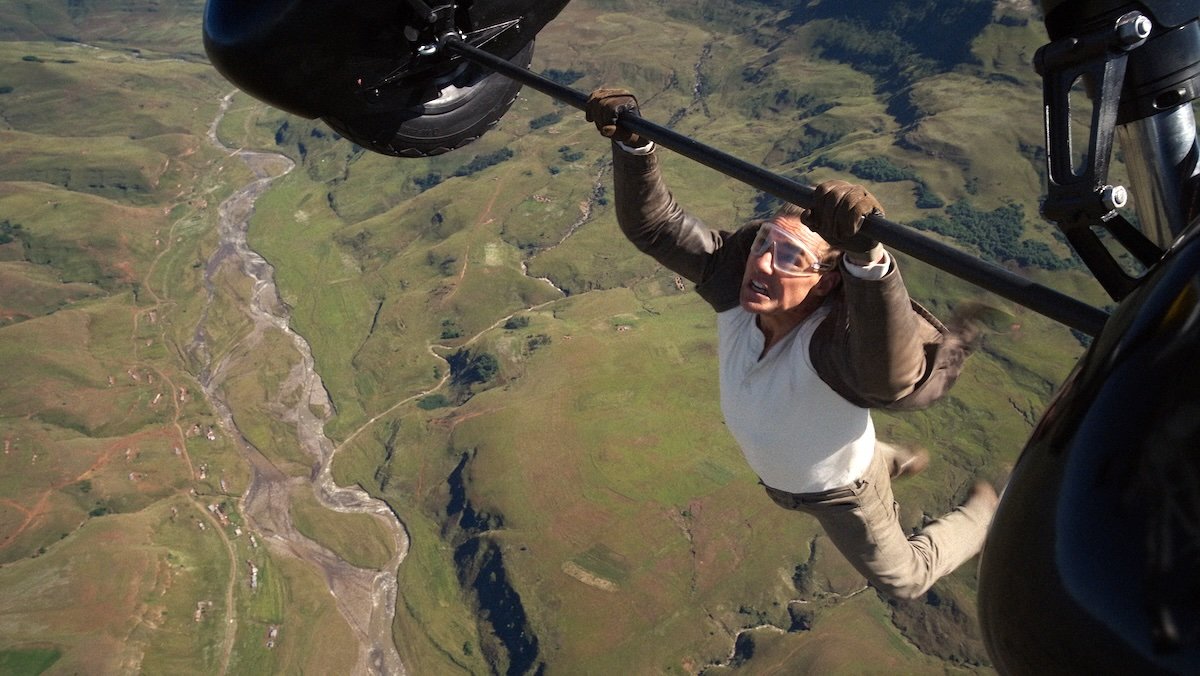 Tom Cruise hanging from a flying biplane high above the ground in Mission: Impossible - The Final Reckoning