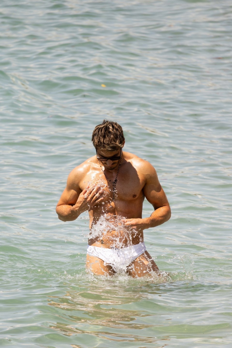 Chris Appleton in white swim trunks wading in the ocean.