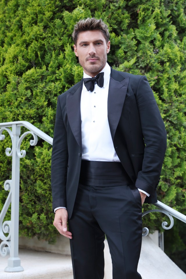 Man in tuxedo standing by railing.