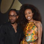Kendrick Lamar and SZA stand in front of a backdrop with a Grammy trophy.