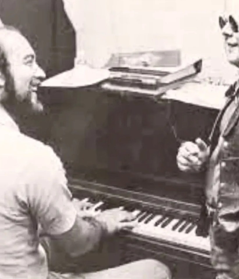 Black and white photo of two men at a piano.