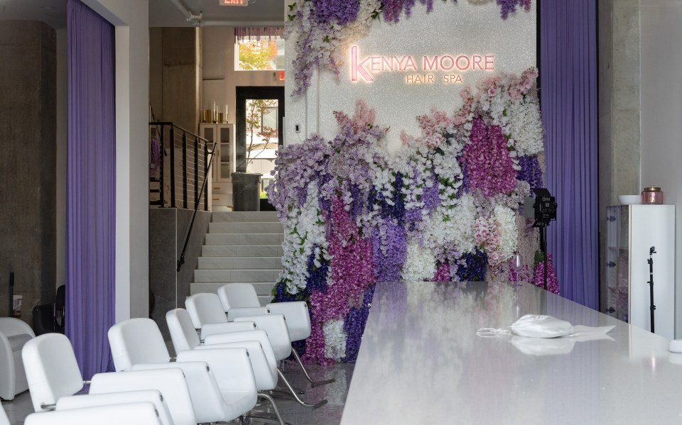 Interior of Kenya Moore Hair Spa, featuring white chairs and a flower wall.