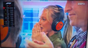 Screenshot of a Formula 1 race broadcast showing race standings and a woman reacting.