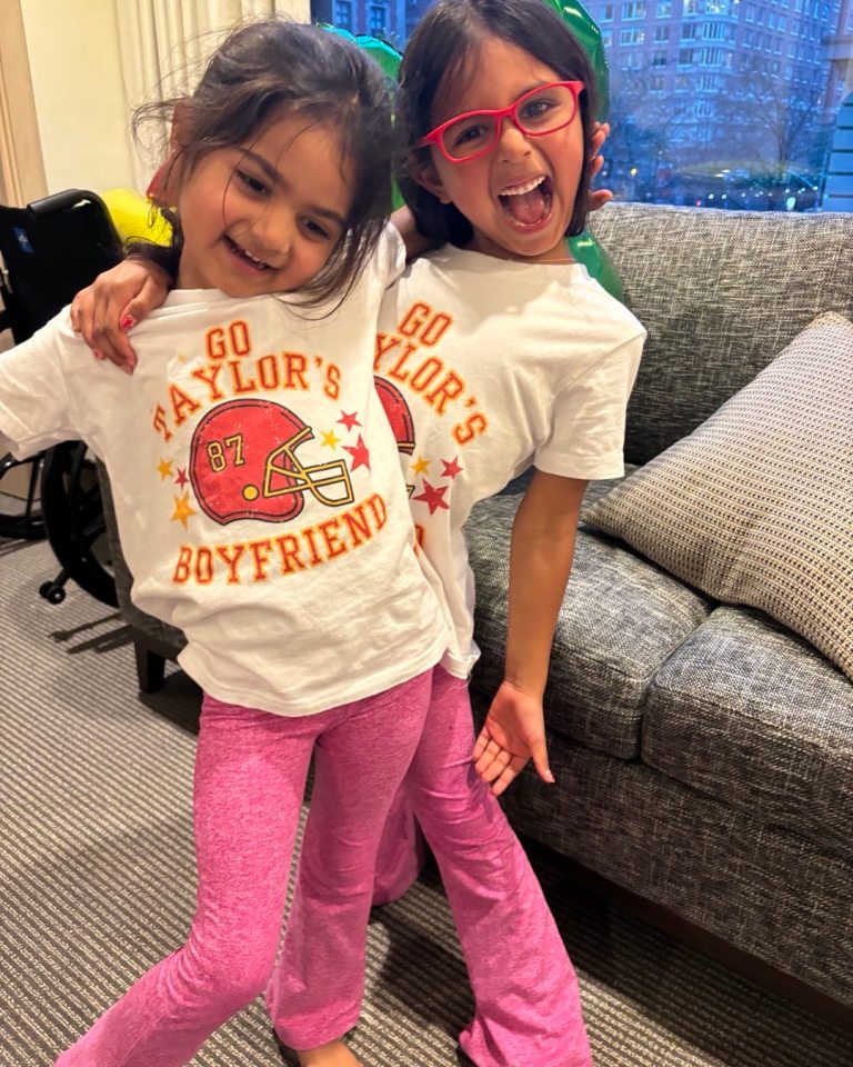 Two girls wearing matching "Go Taylor's Boyfriend" shirts.