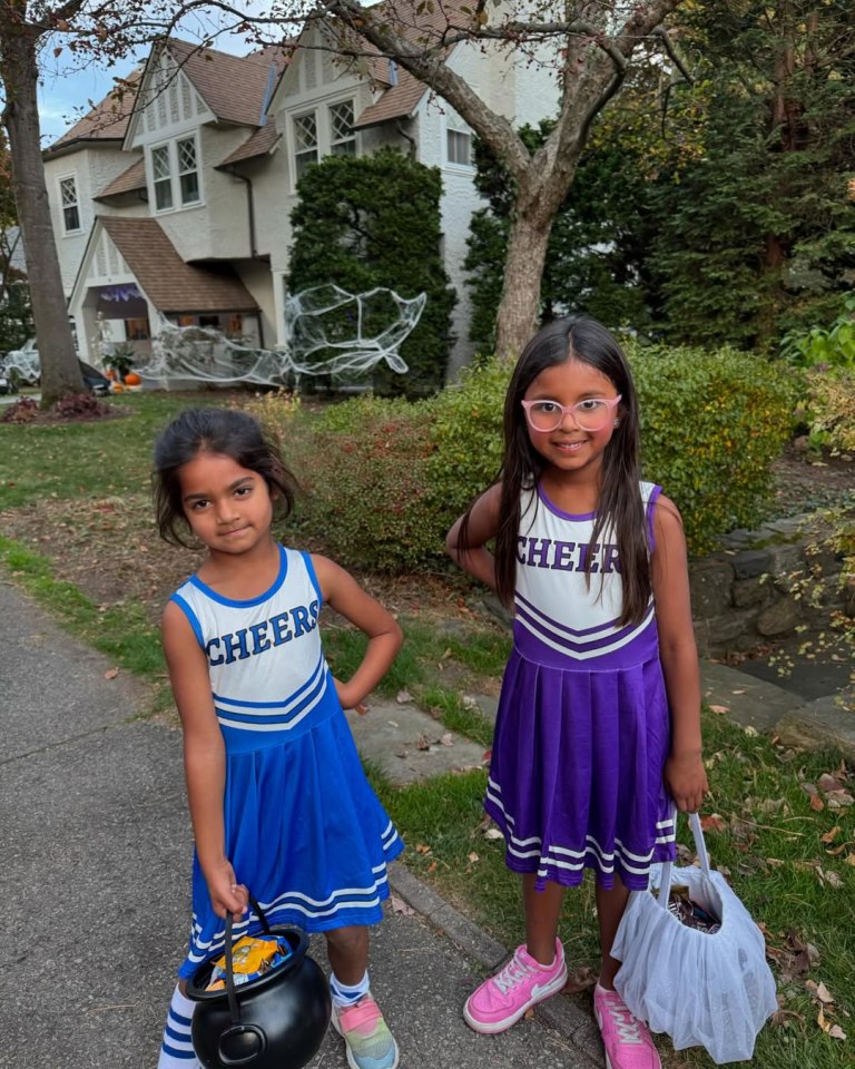 Two girls in cheerleader costumes trick-or-treating.