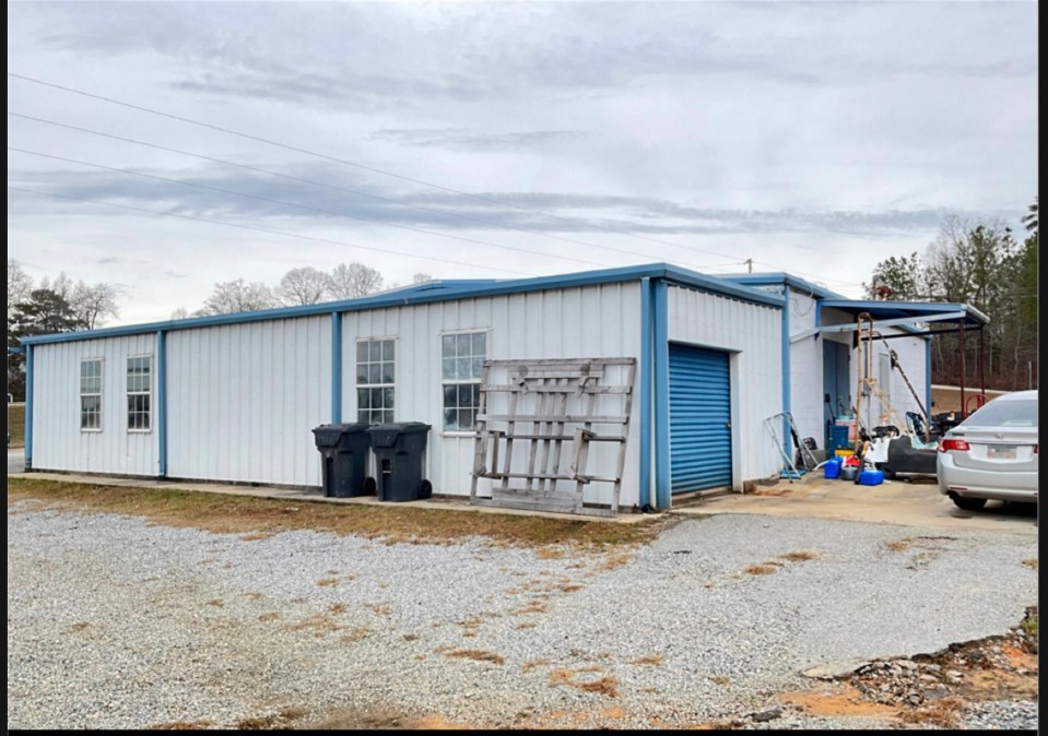 Exterior view of a white metal building with a blue roll-up door.
