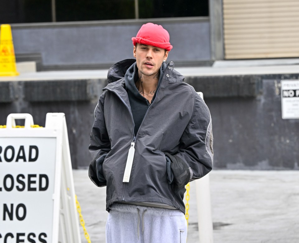 Justin Bieber wearing a red hat and dark jacket.
