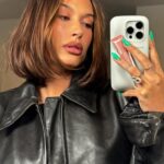 Hailey Bieber selfie holding rhode lip treatment.