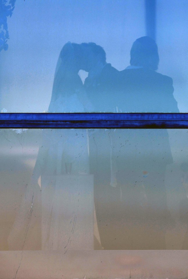Silhouette of a couple kissing through glass.
