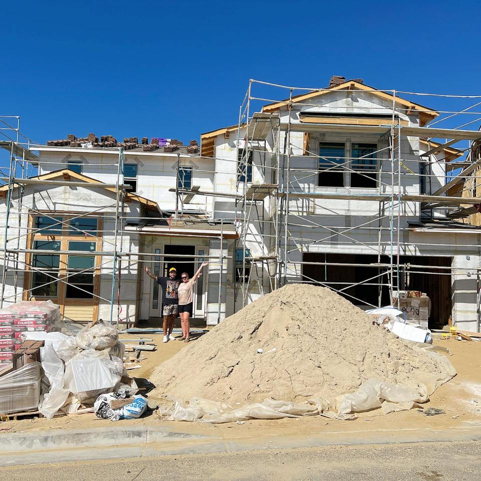 Couple standing in front of a house under construction.