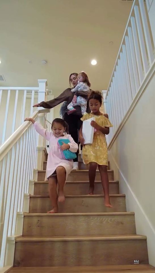 Woman carrying a baby and two girls descending stairs.