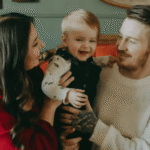 Family portrait of parents holding their laughing baby.