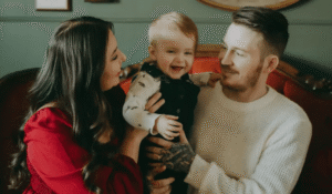 Family portrait of parents holding their laughing baby.