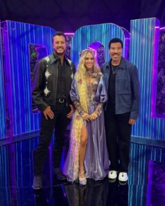 Luke Bryan, Carrie Underwood, and Lionel Richie posing together.