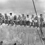 While New York's thousands rush to crowded restaurants and congested lunch counters for their noon day lunch, these intrepid steel workers atop the 70 story RCA building in Rockefeller Center get all the air and freedom they want by lunching on a steel beam with a sheer drop of over 800 feet to the street level. The RCA building is the largest office building in terms of office space in the world. (original caption). Image taken 9/20/32; filed 9/29/32.