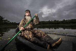 Phil Robertson of Duck Dynasty in a boat on a swamp.