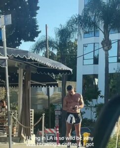 A shirtless man resembling Colin Farrell outside a coffee shop.