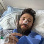 Stanislav Yanevski, a Bulgarian actor, in a hospital bed with an IV and a bandage on his nose.