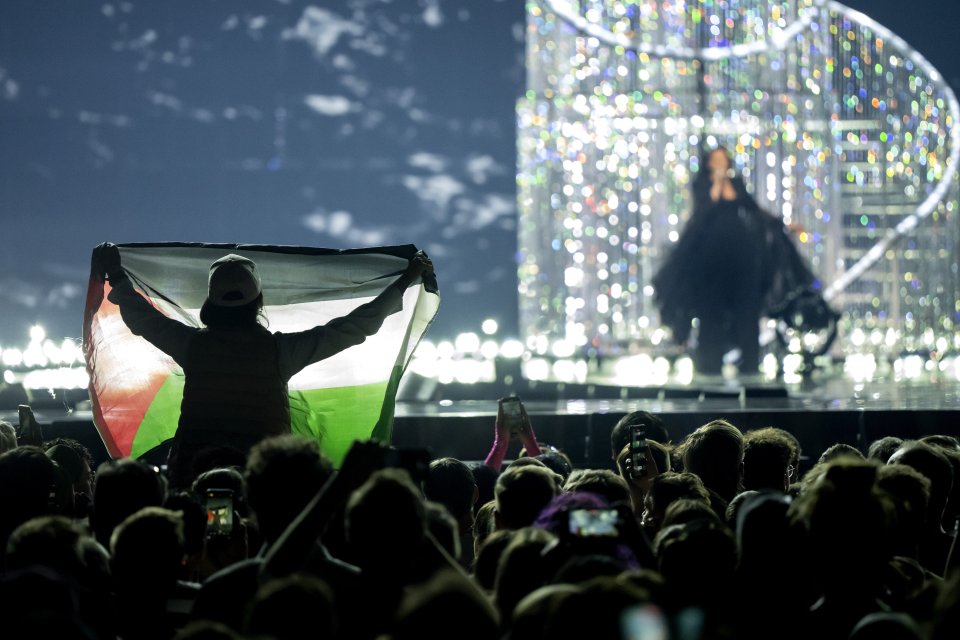 A person holds up a Palestinian flag at a concert.
