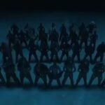 Screenshot of a music video showing a large group of shirtless men in silhouette.