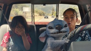 Maia Kealoha and Sydney Agudong ride in a truck as blue alien Stitch grabs the wheel in a still from 'Lilo & Stitch'.