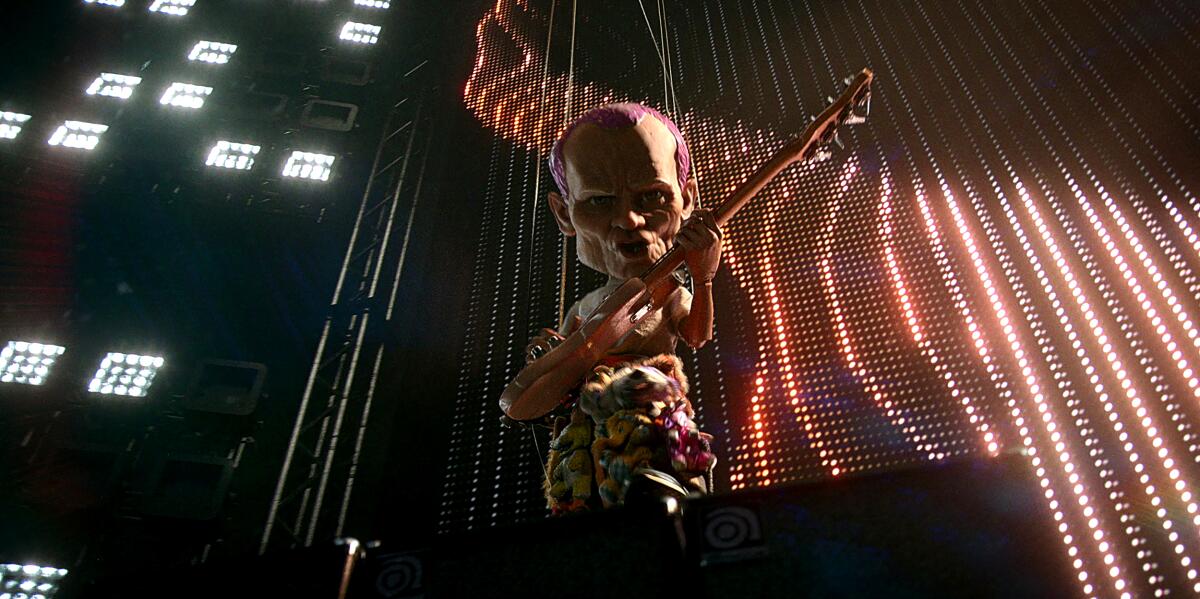 A man as a string puppet playing a bass guitar.